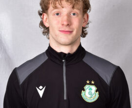 Young Shamrock Rovers player in team training kit, smiling at camera.