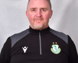 Portrait of Shamrock Rovers coach in team gear, smiling confidently.