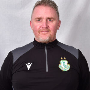 Portrait of Shamrock Rovers coach in team gear, smiling confidently.