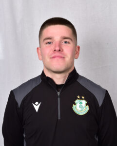 Young Shamrock Rovers player in team jacket, smiling confidently.