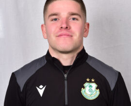 Young Shamrock Rovers player in team jacket, smiling confidently.