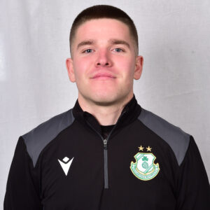 Young Shamrock Rovers player in team jacket, smiling confidently.