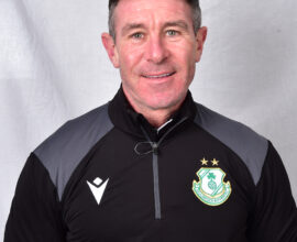 Shamrock Rovers coach in team gear, smiling, standing against a plain background.