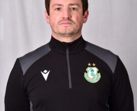 Shamrock Rovers coach in team training gear, standing confidently in front of a plain background.