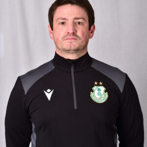 Shamrock Rovers coach in team training gear, standing confidently in front of a plain background.
