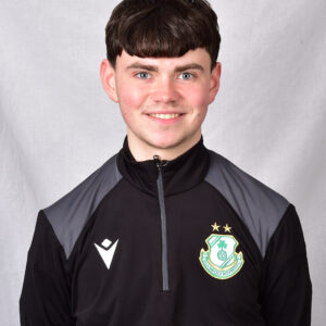 Young Shamrock Rovers player in team training jacket smiling at camera.