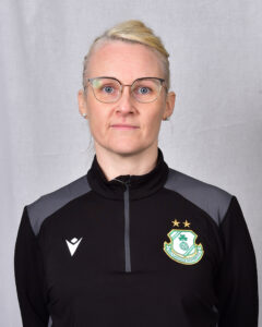 Female Shamrock Rovers player in team jacket with club crest.