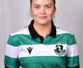 Female Shamrock Rovers player in green and white jersey smiling outdoors.