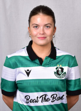 Female Shamrock Rovers player in green and white jersey smiling outdoors.