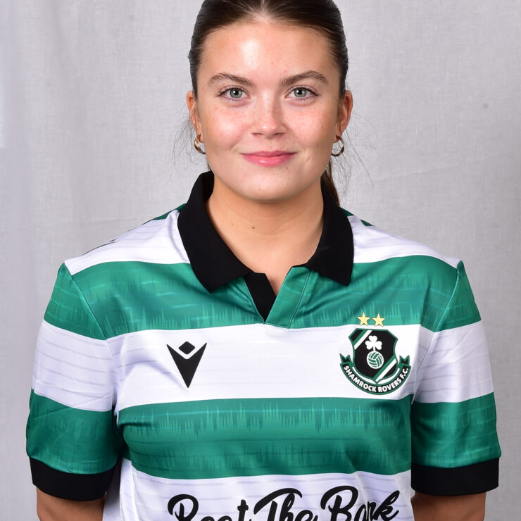 Female Shamrock Rovers player in green and white jersey smiling outdoors.