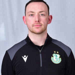 Shamrock Rovers football player in team kit with club crest, facing forward.