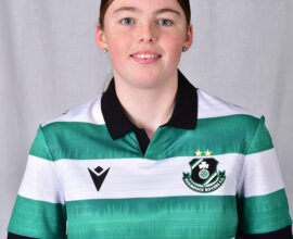 Female Shamrock Rovers player in team jersey smiling at camera.