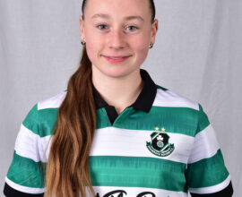 Shamrock Rovers female football player in team jersey, smiling confidently.