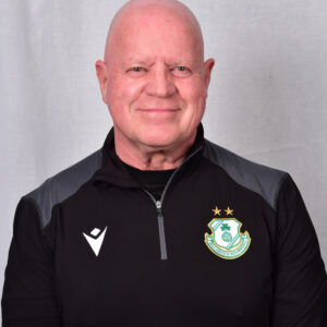 Shamrock Rovers coach in team gear, smiling, standing against a neutral background.