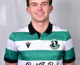 Young Shamrock Rovers footballer in green and white kit smiling at camera.