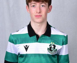 Young Shamrock Rovers player in team jersey, standing against grey background.