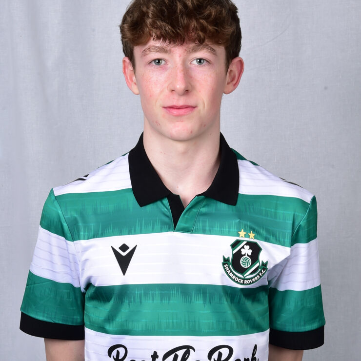 Young Shamrock Rovers player in team jersey, standing against grey background.