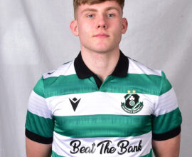 Young Shamrock Rovers footballer in green and white kit, standing confidently.