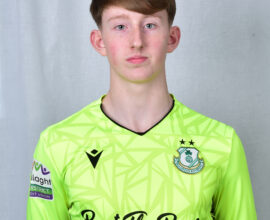 Young Shamrock Rovers goalkeeper in bright green kit with club crest.