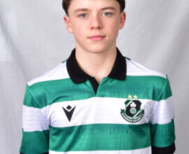 Young Shamrock Rovers player in team jersey, standing against a grey background.