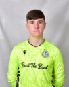 Young Shamrock Rovers goalkeeper in bright green jersey, facing forward.
