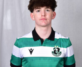 Young Shamrock Rovers player in team jersey, standing against a grey background.