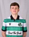 Young Shamrock Rovers player in green and white kit smiling at camera.