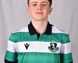 Young Shamrock Rovers player in green and white kit smiling at camera.
