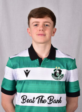 Young Shamrock Rovers player in green and white kit smiling at camera.