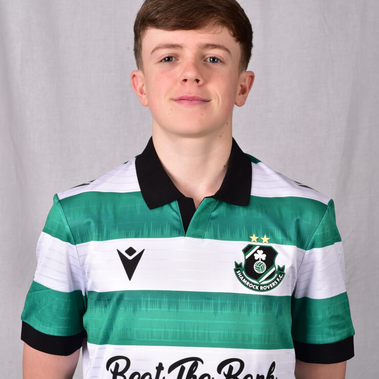 Young Shamrock Rovers player in green and white kit smiling at camera.