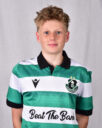 Young Shamrock Rovers player in green and white kit, smiling at camera.