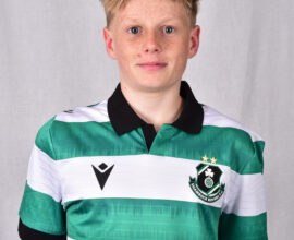 Young Shamrock Rovers player in green and white kit, smiling at camera.