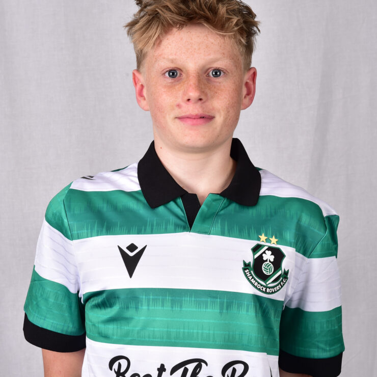 Young Shamrock Rovers player in green and white kit, smiling at camera.