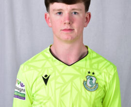 Young Shamrock Rovers player in bright green kit, standing against a grey background.