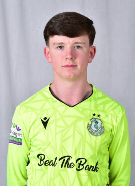 Young Shamrock Rovers player in bright green kit, standing against a grey background.