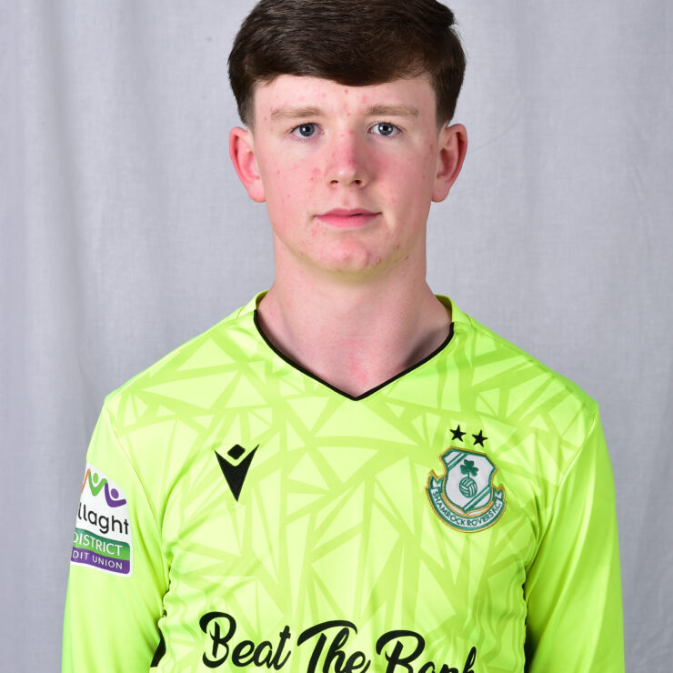 Young Shamrock Rovers player in bright green kit, standing against a grey background.