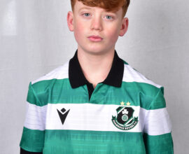 Young Shamrock Rovers player in green and white jersey, standing against a grey background.