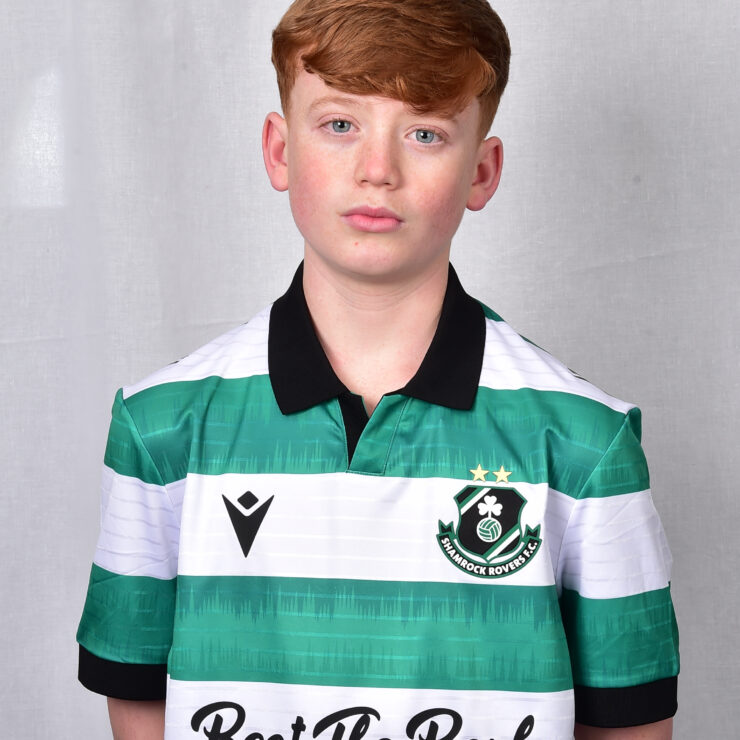 Young Shamrock Rovers player in green and white jersey, standing against a grey background.