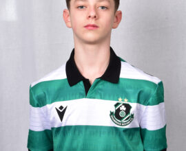 Young Shamrock Rovers player in team jersey, standing against grey background.