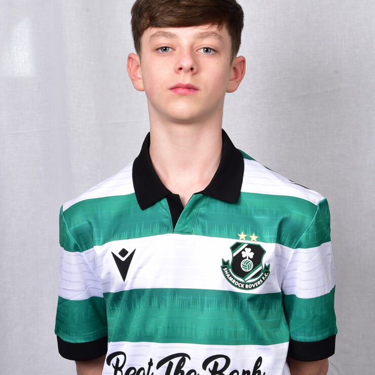 Young Shamrock Rovers player in team jersey, standing against grey background.