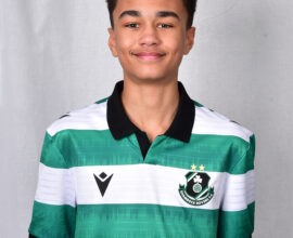 Young Shamrock Rovers player in green and white jersey smiling.