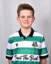 Young Shamrock Rovers player in team jersey smiling at camera.