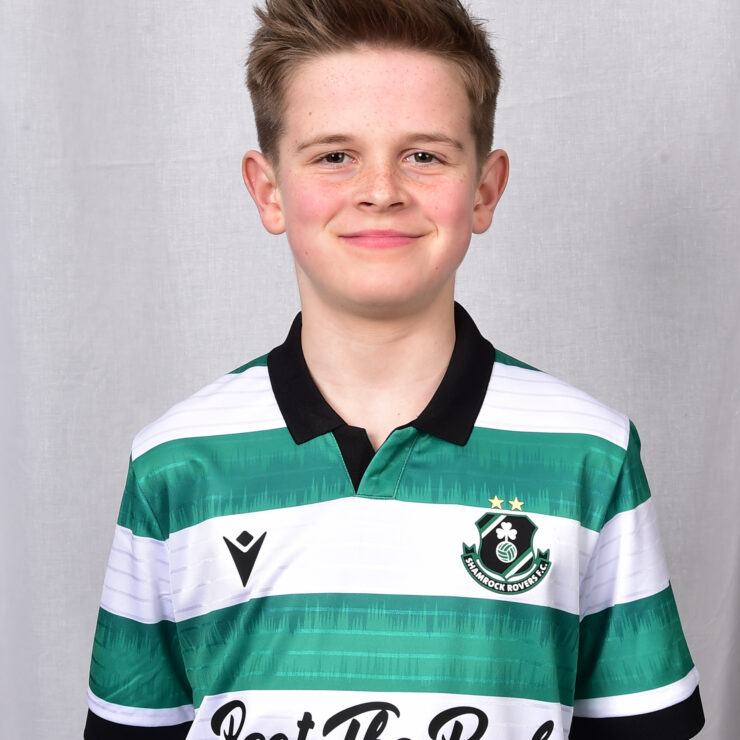 Young Shamrock Rovers player in team jersey smiling at camera.