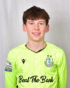Young Shamrock Rovers player in bright green jersey smiling at camera.