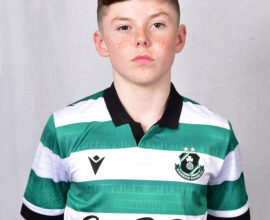 Young Shamrock Rovers player in green and white kit, standing confidently.