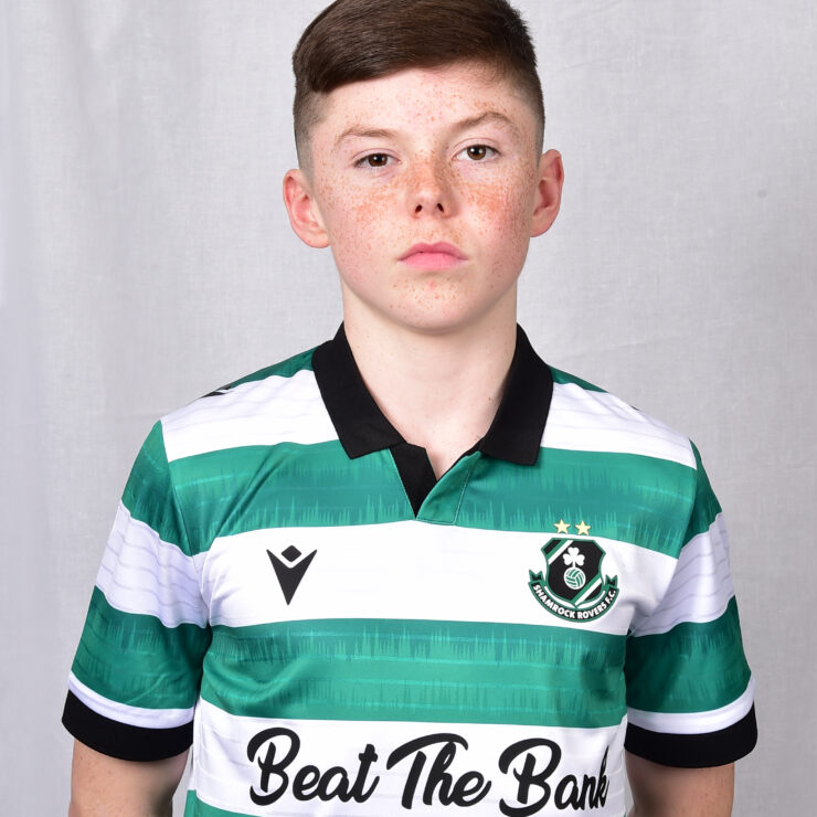 Young Shamrock Rovers player in green and white kit, standing confidently.