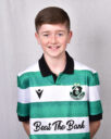 Young Shamrock Rovers player in team jersey smiling.
