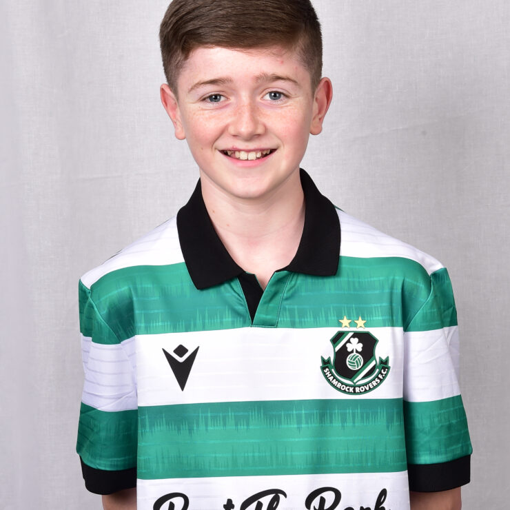 Young Shamrock Rovers player in team jersey smiling.