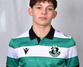 Young Shamrock Rovers player in green and white jersey, standing against a grey background.