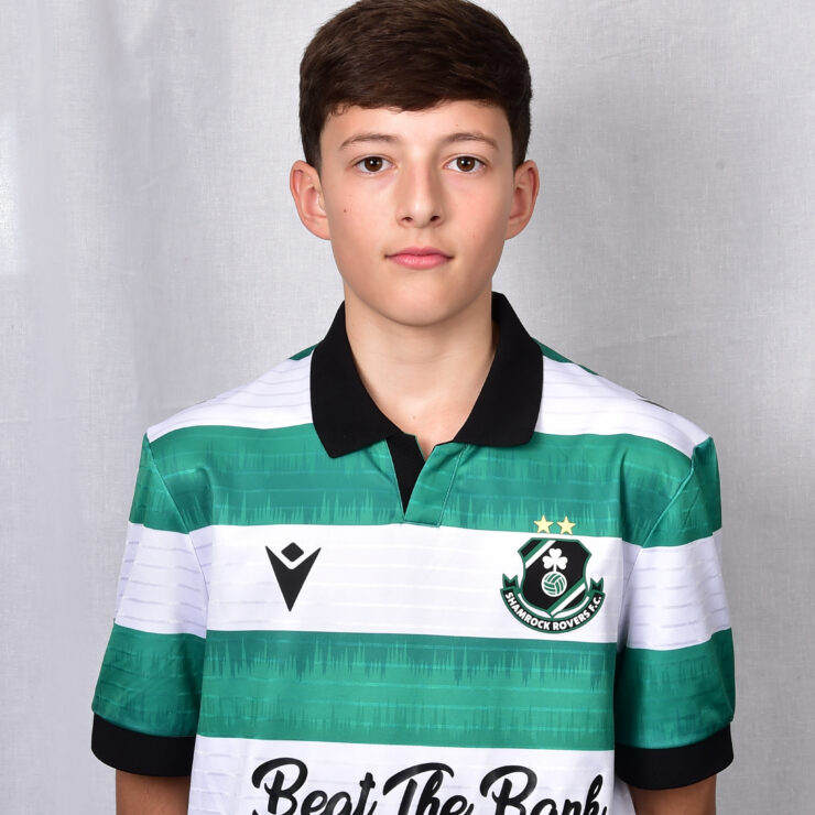 Young Shamrock Rovers player in green and white jersey, standing against a grey background.